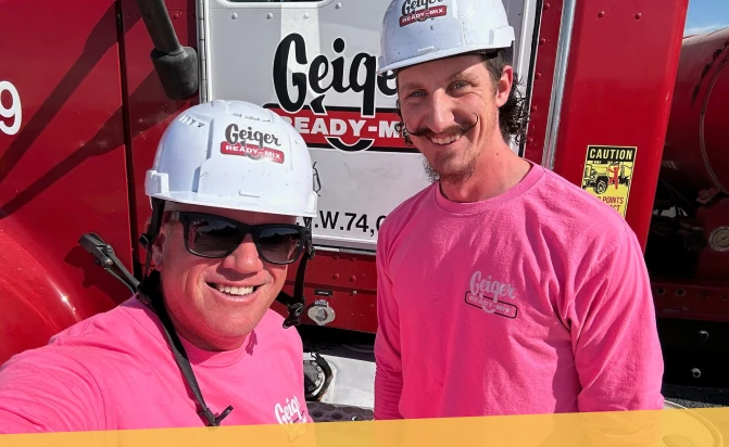Two Geiger employees wearing hard hats in front of Geiger truck